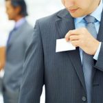 A man in a suit putting on a name tag.