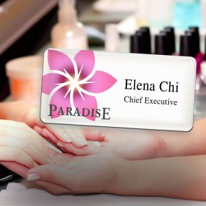 Nail salon tech with customer and a full color logo tag.