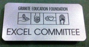 Engraved metal logo name tag with a magnetic fastener; Granite Education Foundation, Excel Committee.